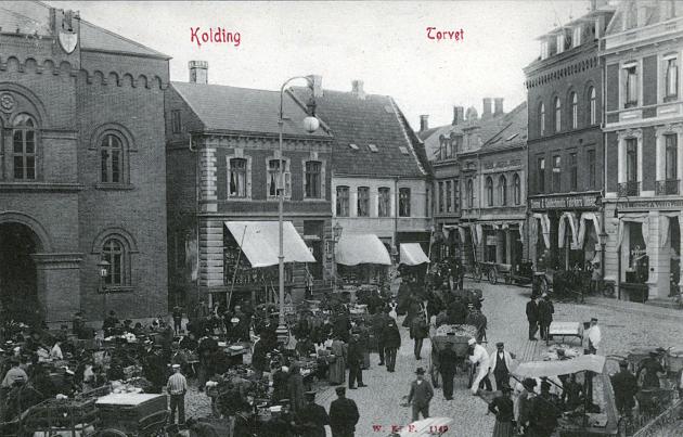 Billede af et torv fyldt med mennesker og hestevogne.