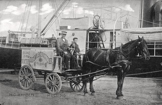 Billede af to mennesker i en hestevogn med et skib i baggrunden.