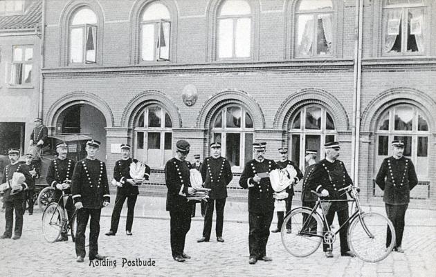 Postbude poserer foran posthuset i Kolding. Et par med cykler.