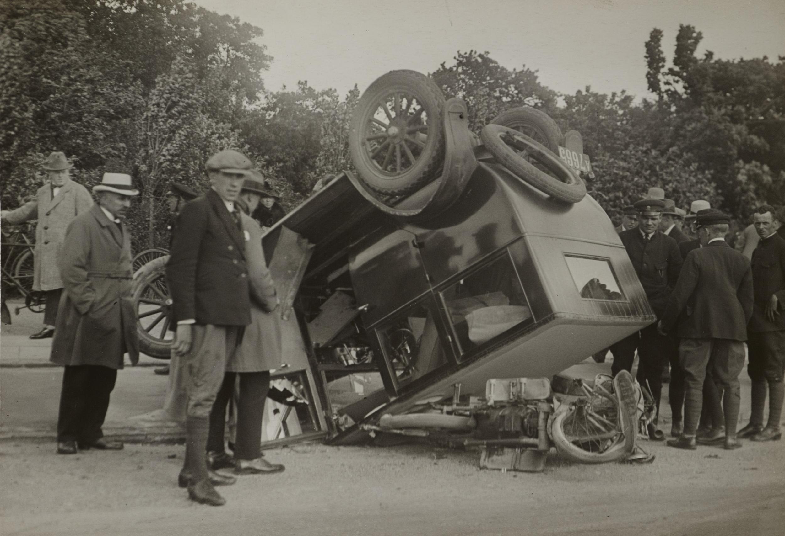 Mennesker omringer en bil, der er væltet på hovedet
