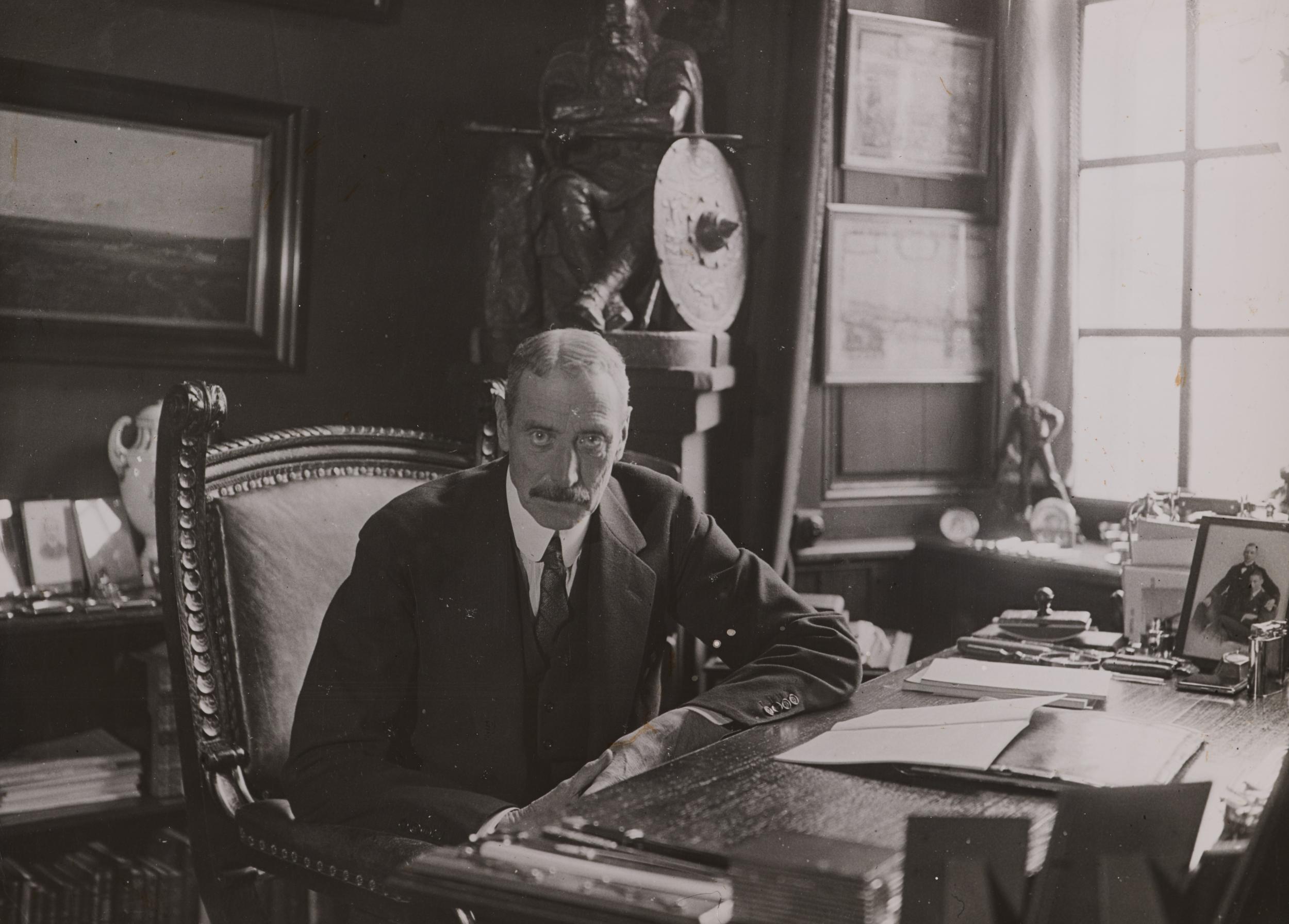 Kong Christian X på sit kontor. Han læner sig over sit skrivebord med blikket rettet mod kameraet.