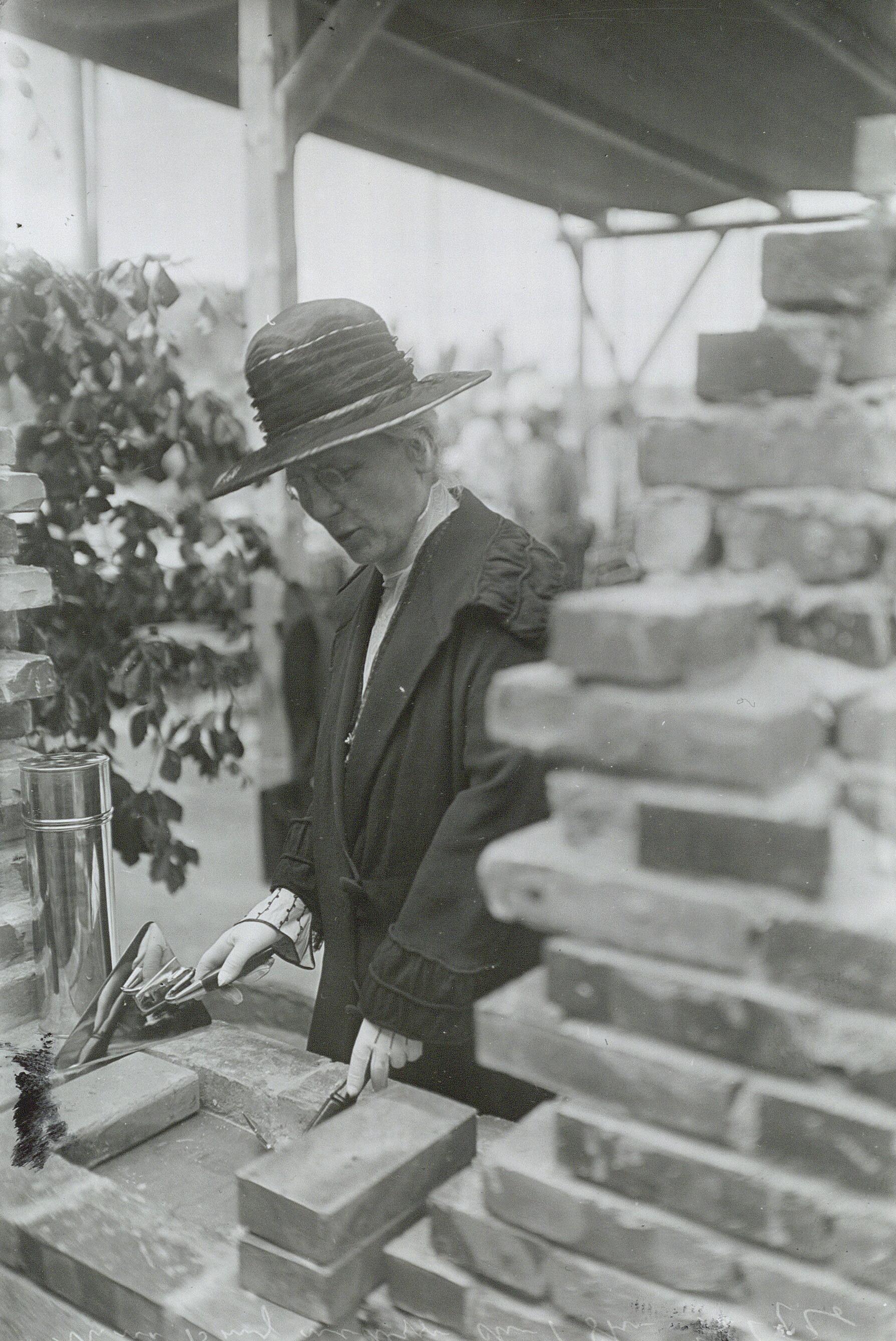 Kvinde iført hat murer en sten