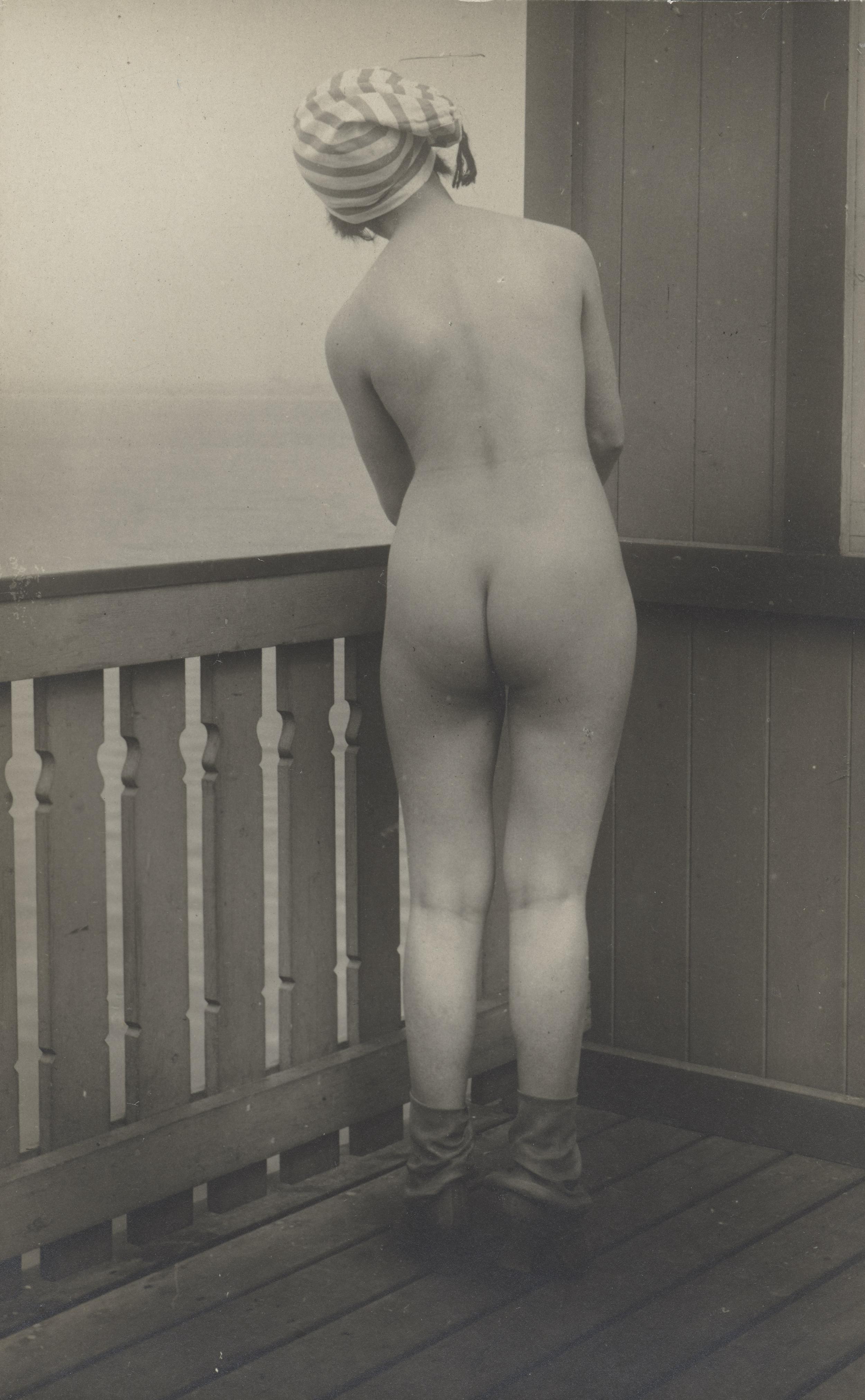 En kvinde med ryggen til kameraet har korte støvler og en hue på, men intet andet