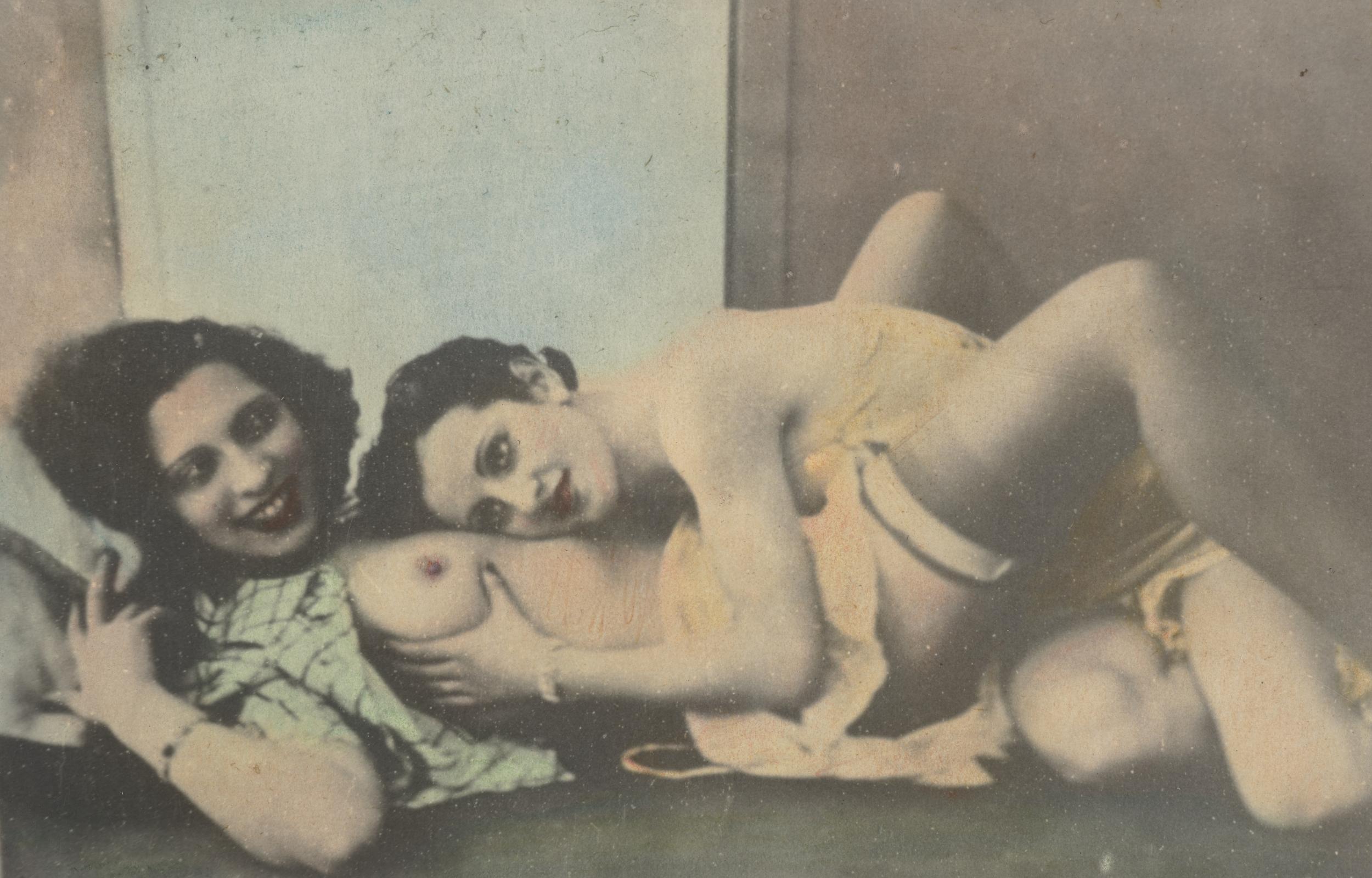 To kvinder ligger sammen, kun halvt påklædt. Den ene har hånden på den andens bryst.