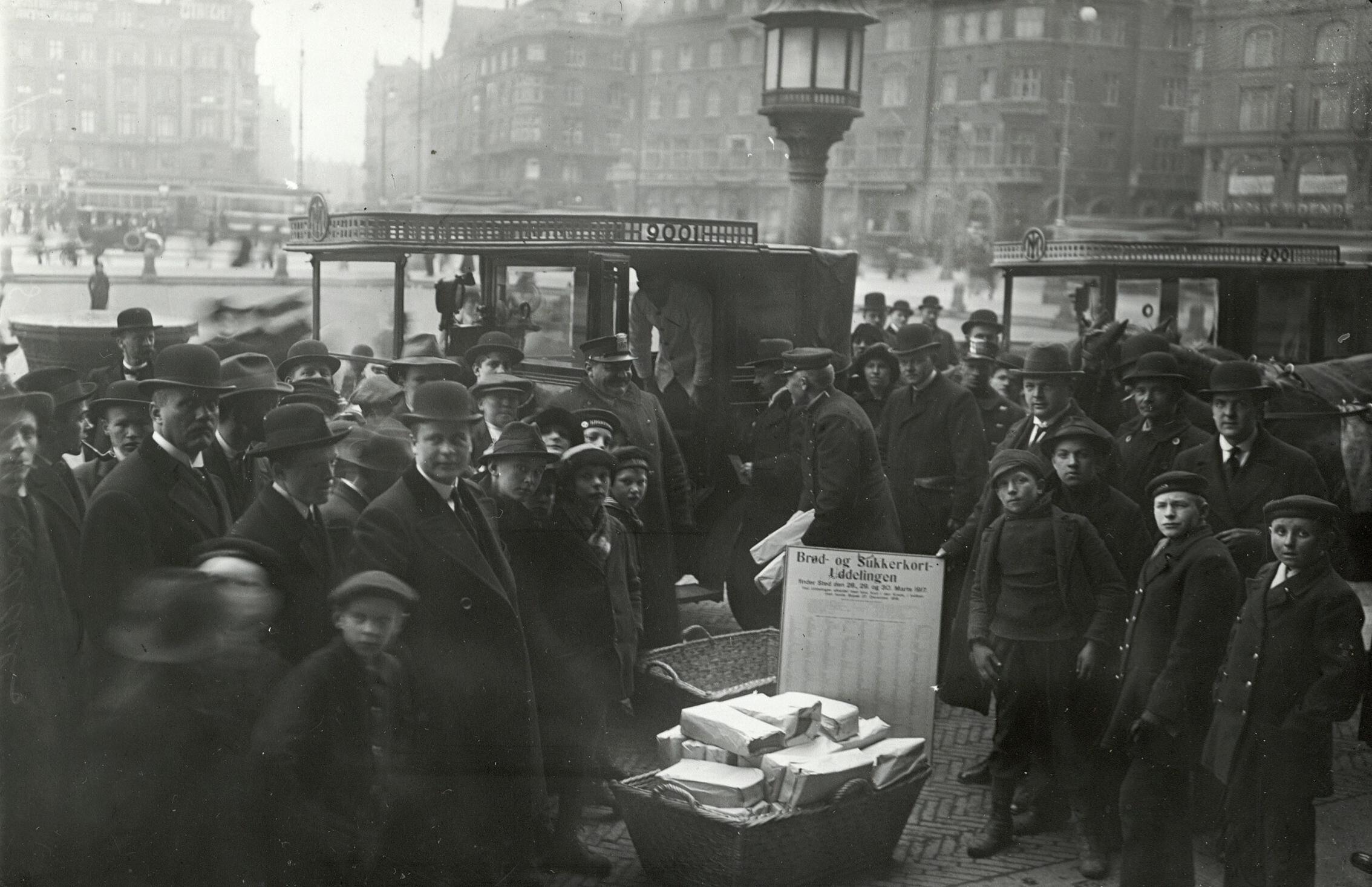 En stor skare mennesker står på en plads, hvor der uddeles rationeringskort.
