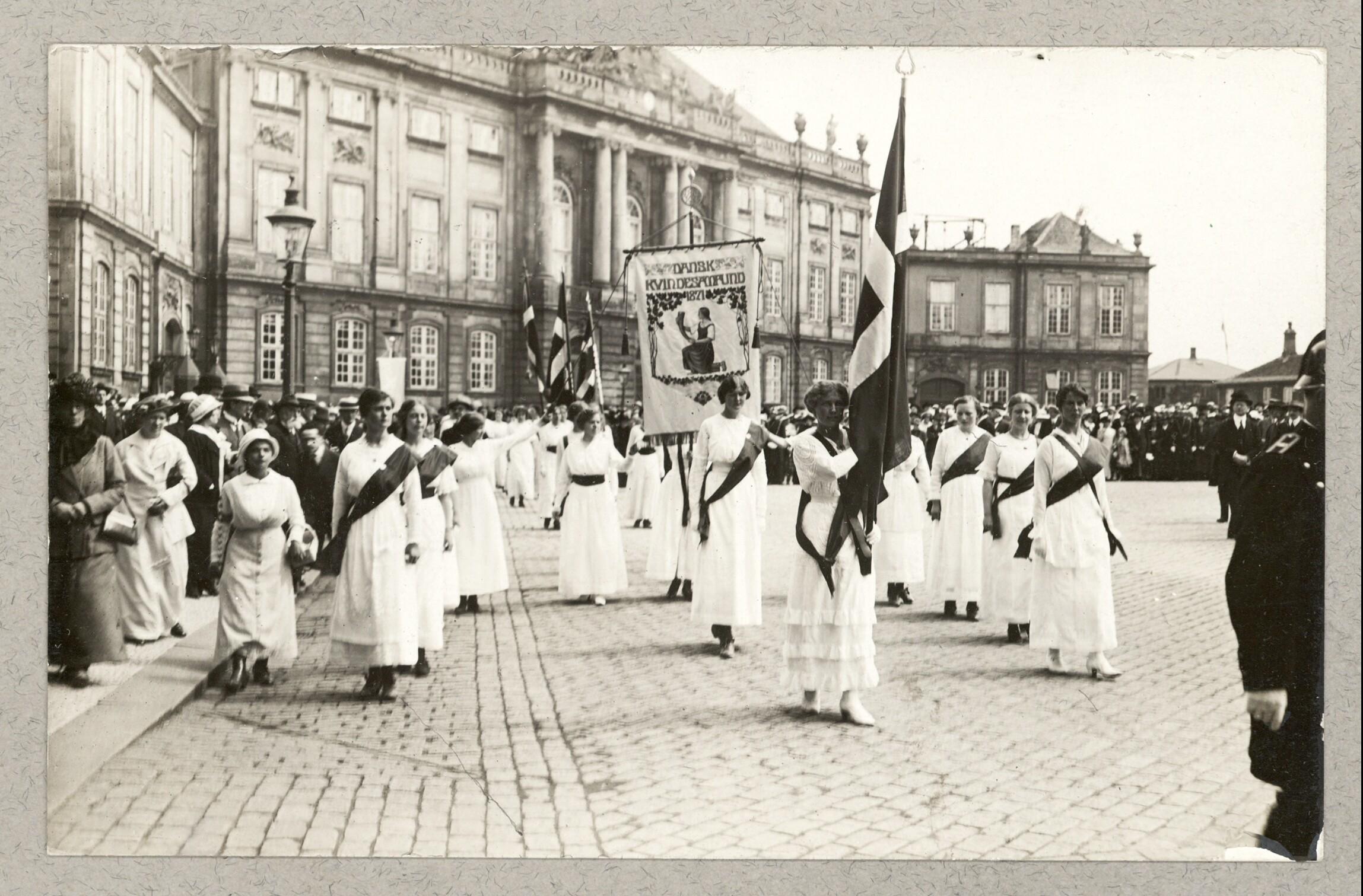 Kvindetoget går forbi Amalienborg med bannere og flag.
