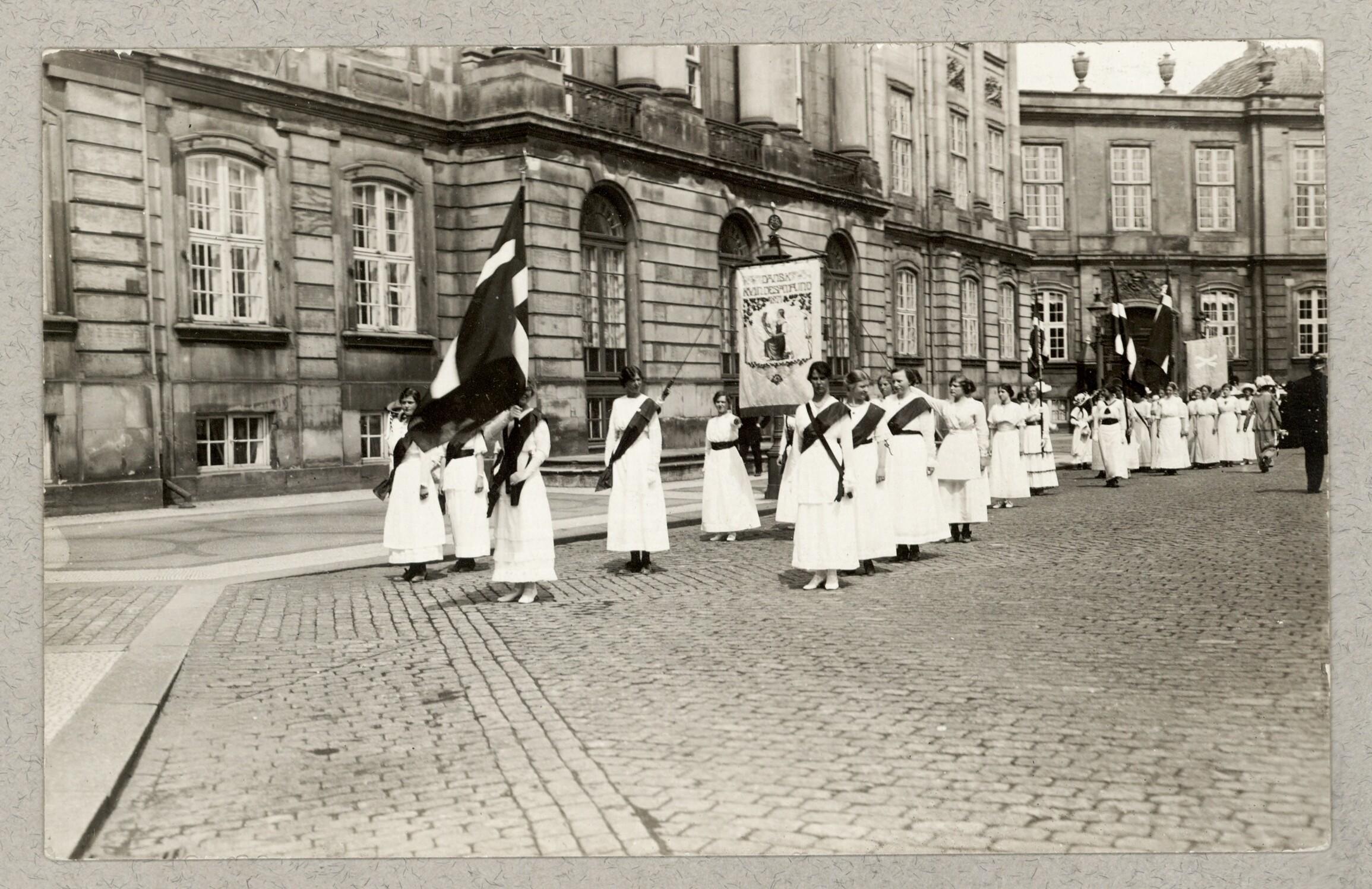 Kvindetoget går forbi Amalienborg med bannere og flag.
