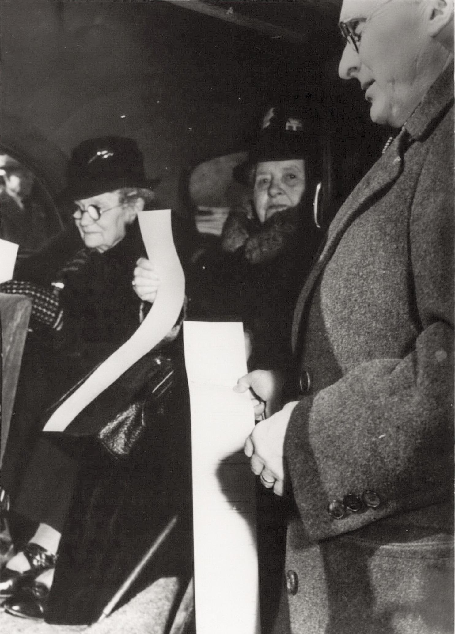Women and men stand with long ballots in their hands