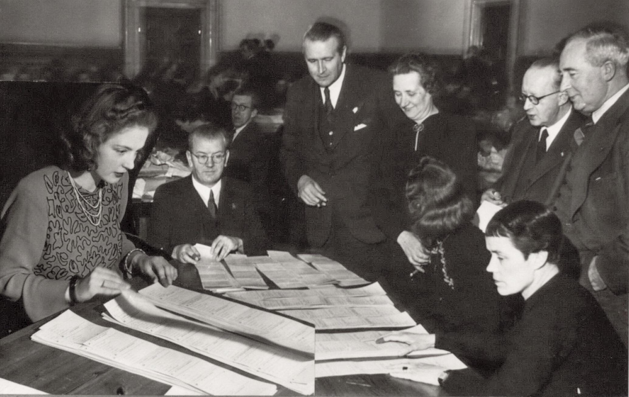 Men and women count votes at tables