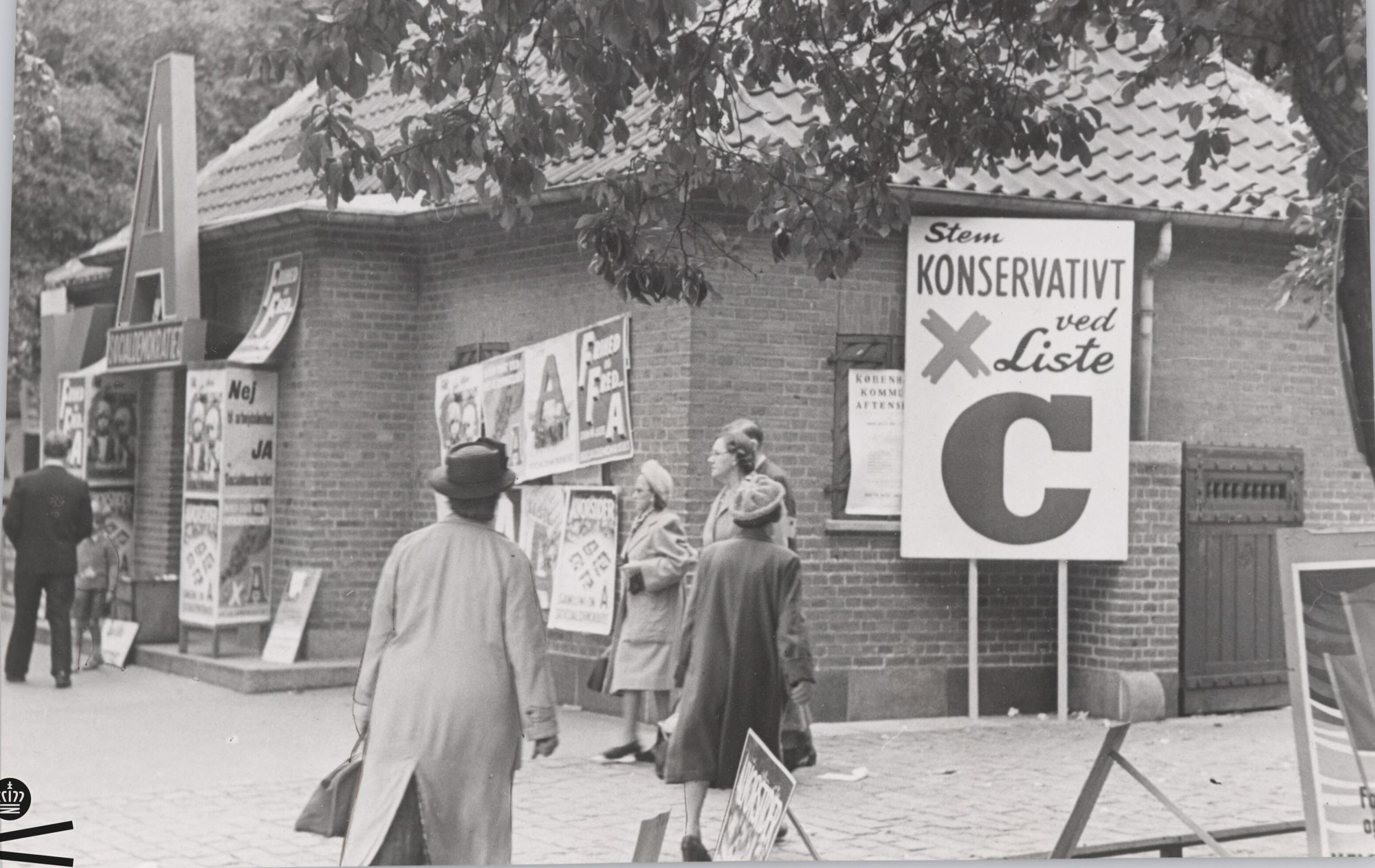 People walk in front of building with election posters