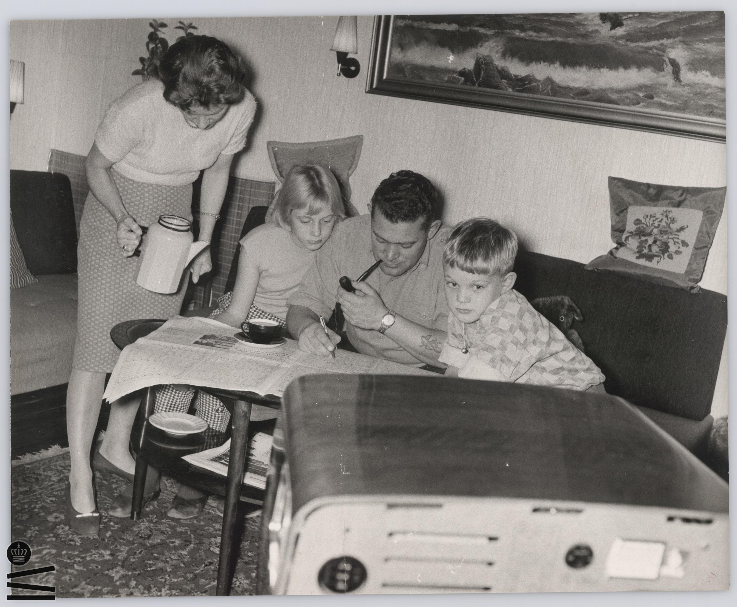 Family sits in front of the TV and looks at the newspaper