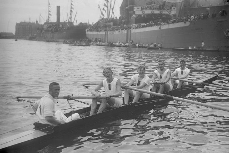 Fotografi af fem mænd i en robåd.