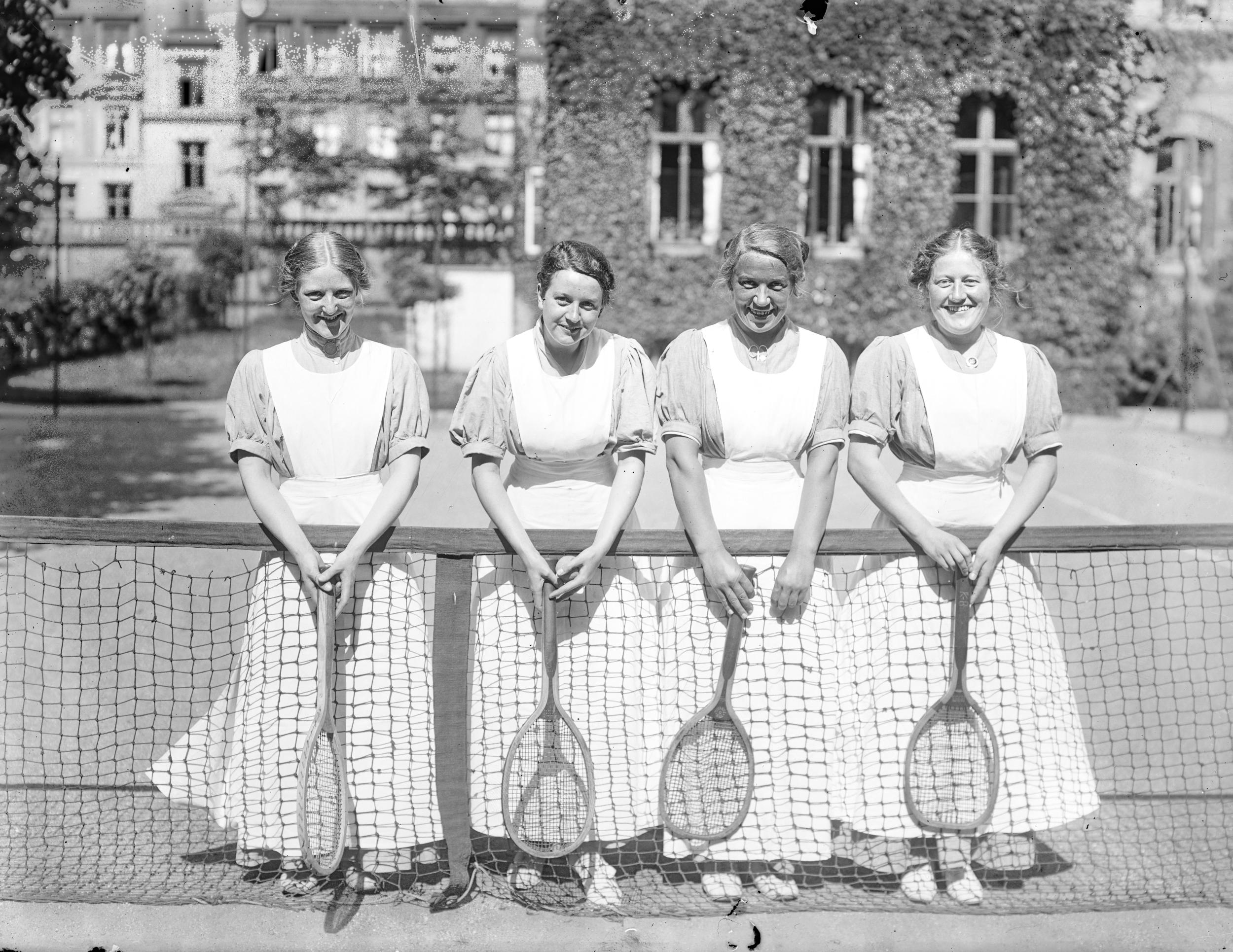 Fotografi af fire kvinder på en tennisbane.
