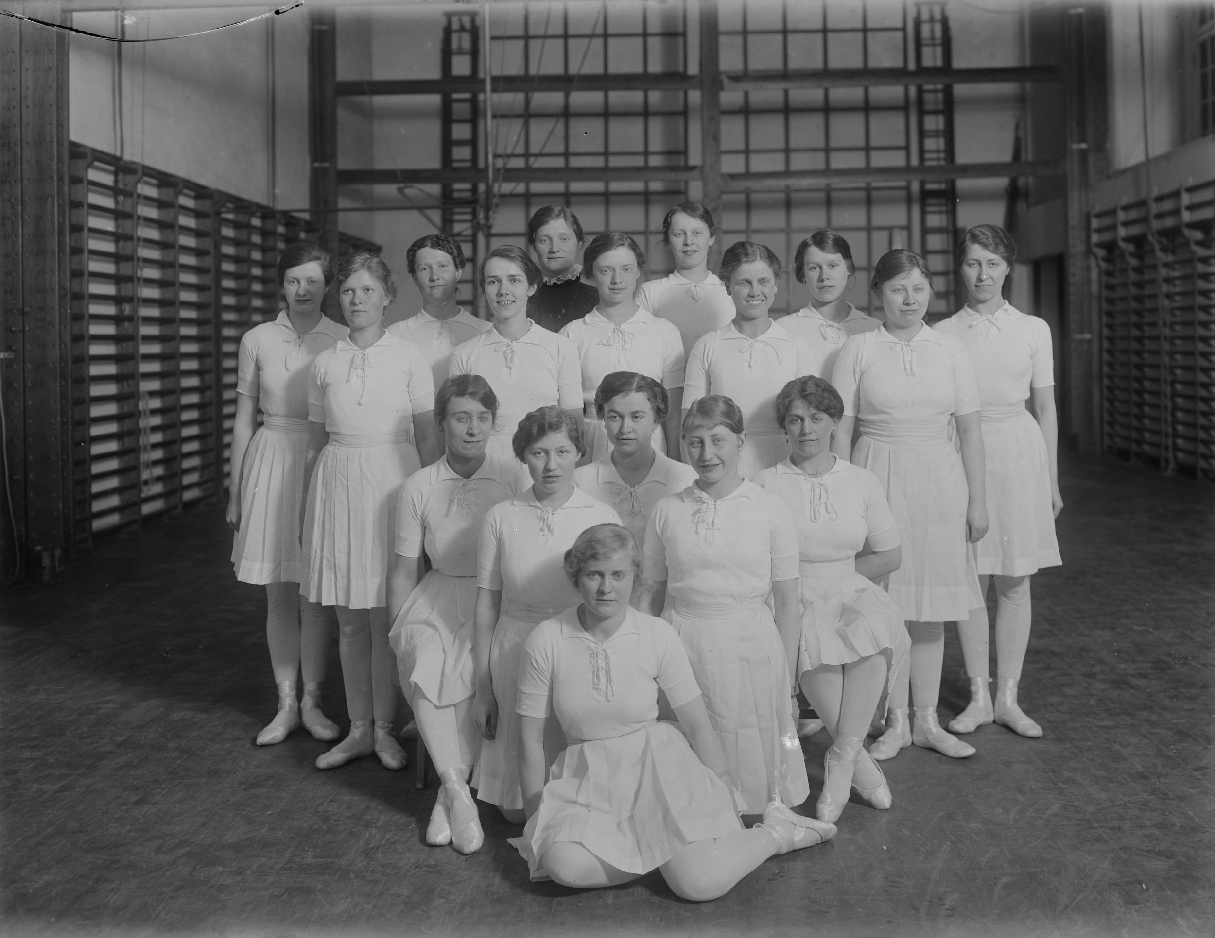 Fotografi af en gruppe kvinder iført gymnastikdragter i en gymnastiksal.