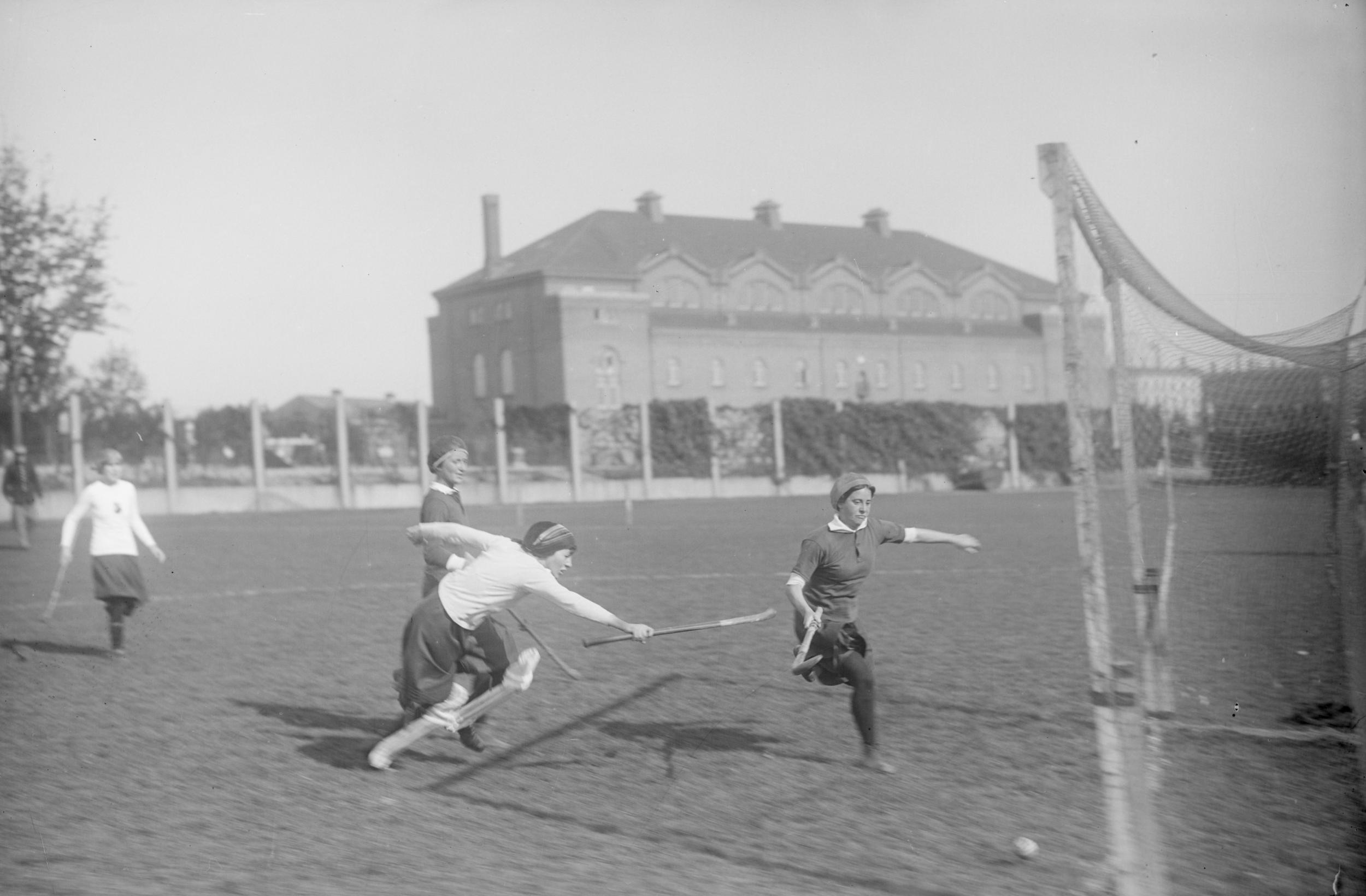 Fire kvinder spiller hockeykamp på græs