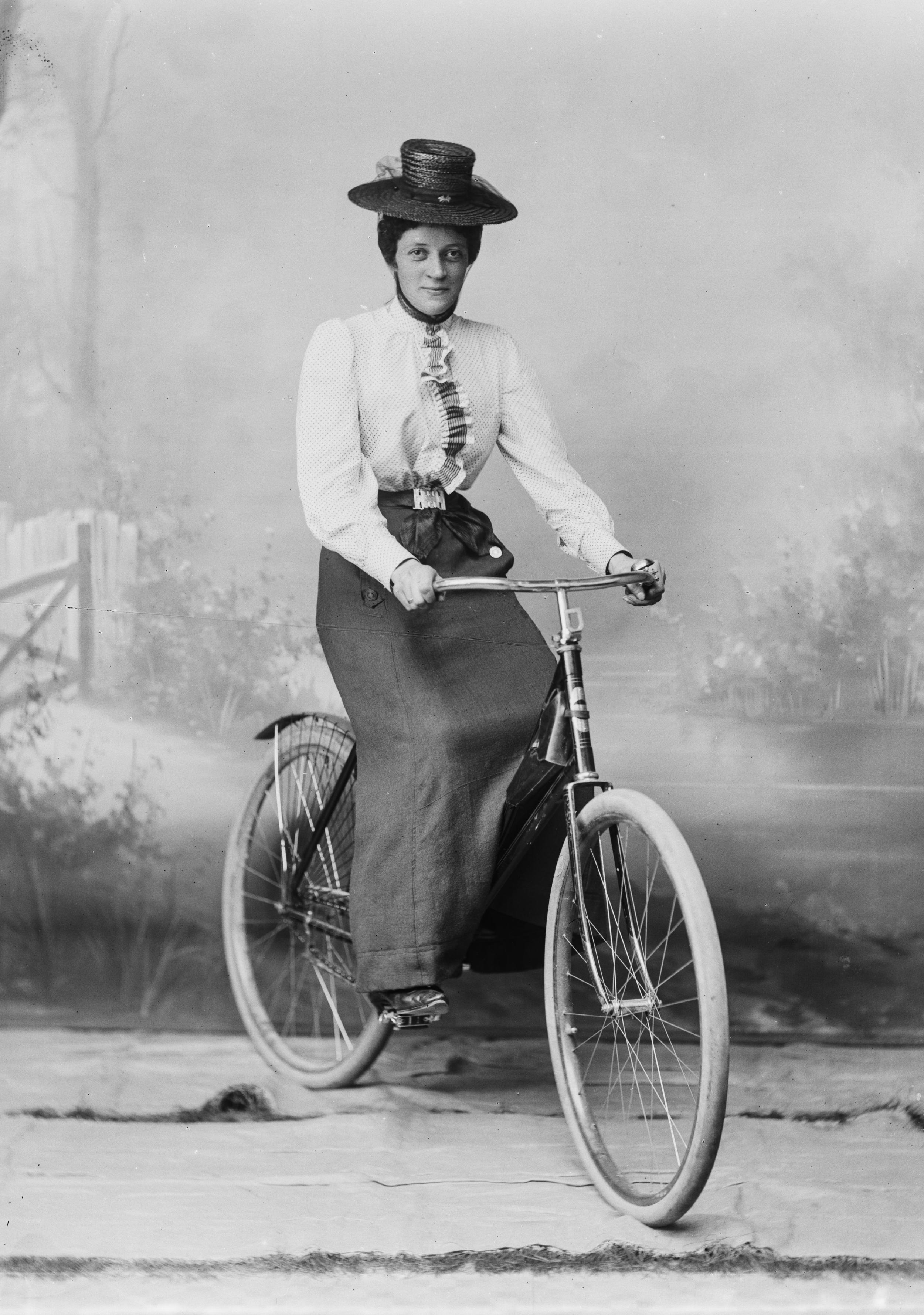 Fotografi af en kvinde i fint tøj på en cykel.