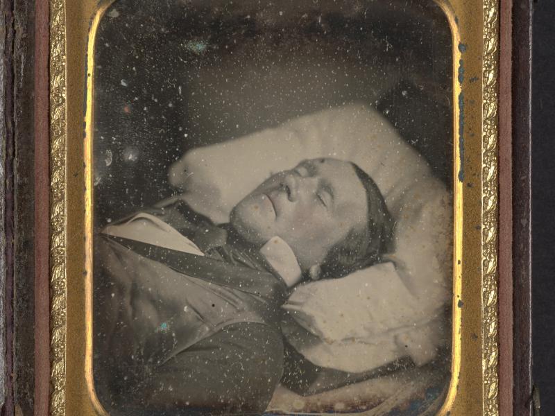 Uidentificeret mand på sit dødsleje. Fotografiet er indrammet i en guldramme.