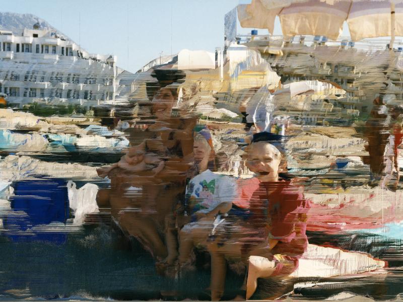 Billede af en kvinde og tre børn på en strand med en udtværet effekt