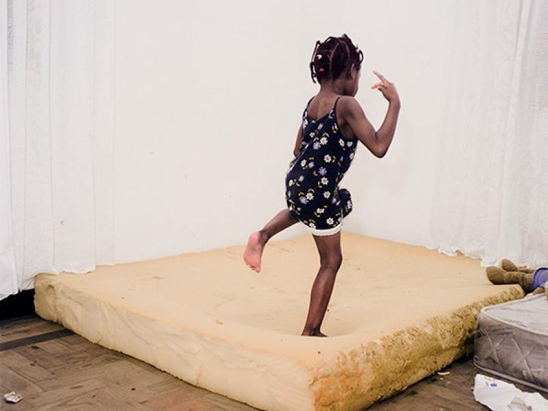 En lille pige danser på en gammel madras i et tomt lokale