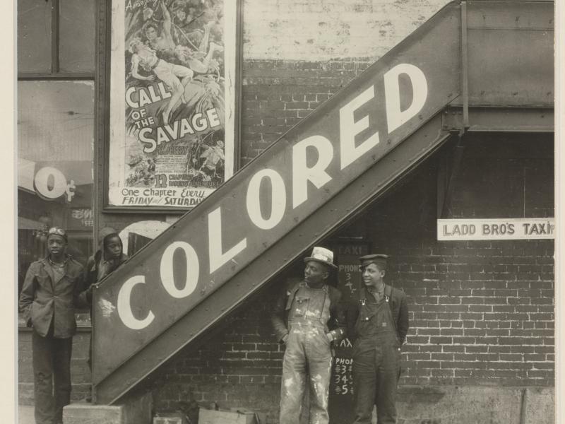 Fire sorte drenge står ved en trappe, der siger 'colored'