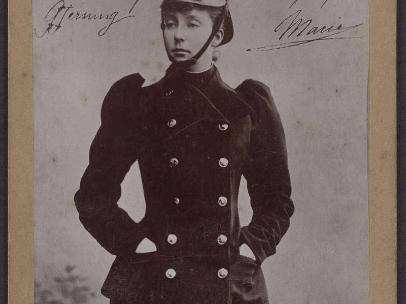 Kabinetkort af Prinsesse Marie af Orléans i en sort branduniform og hat. Hun har hænderne i lommen og ser til siden.