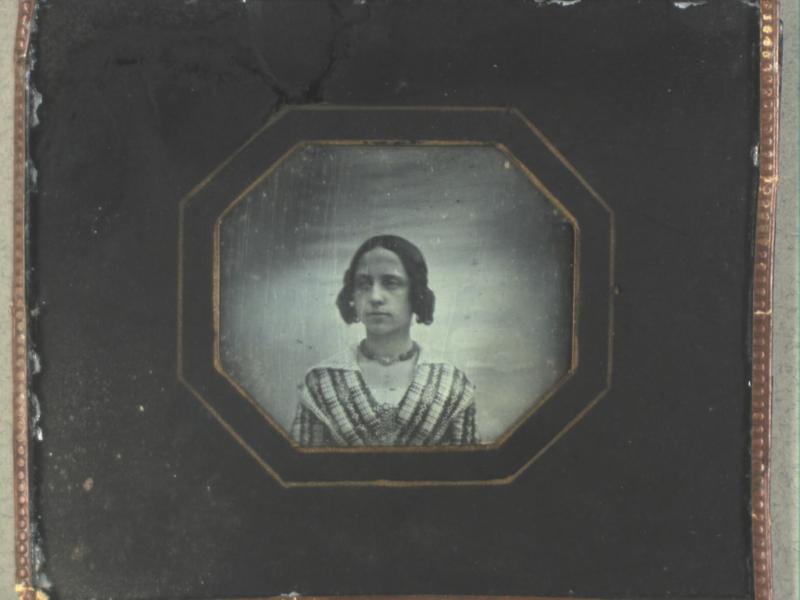 Et gammelt og slidt portræt af en ung kvinde med håret sat op.