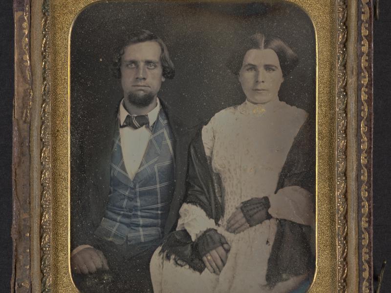 Mand og kvinde sidder side om side. De er klædt flot på. 1800-tallet.