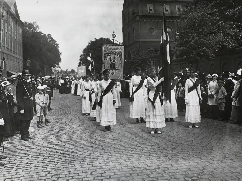 Kvindetoget på vej mod Amalienborg. Kvinderne bærer hvide kjole og bannere.