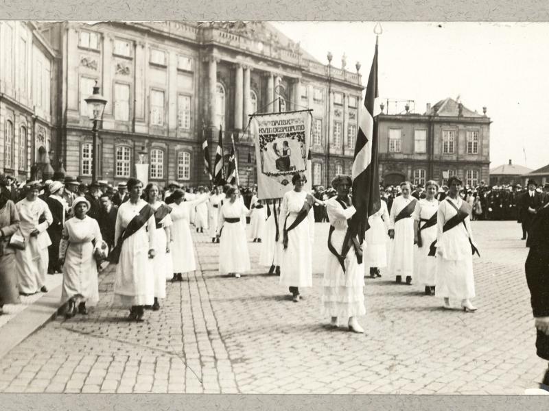 Kvindetoget går forbi Amalienborg med bannere og flag.