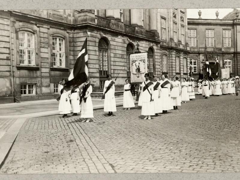 Kvindetoget går forbi Amalienborg med bannere og flag.