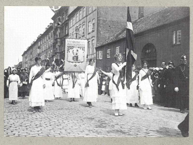 Kvindetoget går igennem København med bannere og flag.