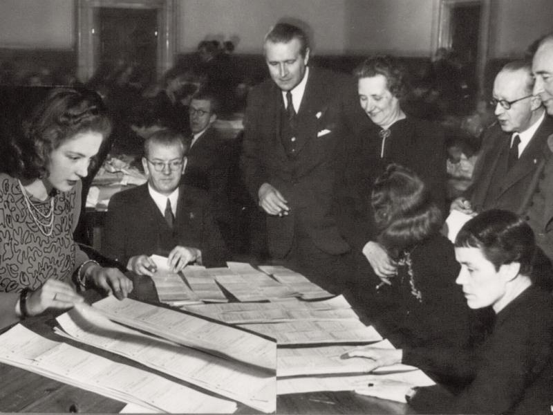 Men and women count votes at tables