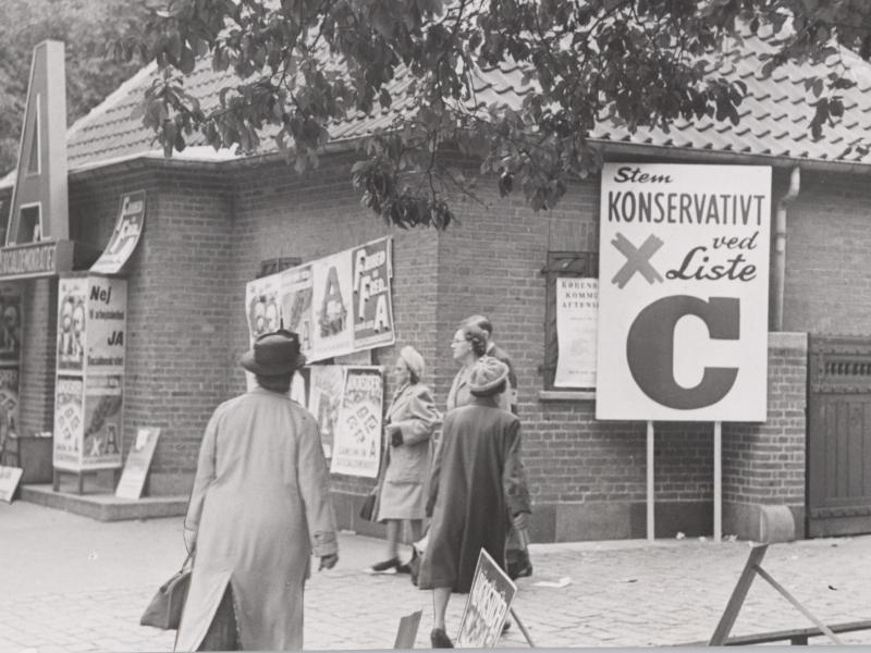 People walk in front of building with election posters