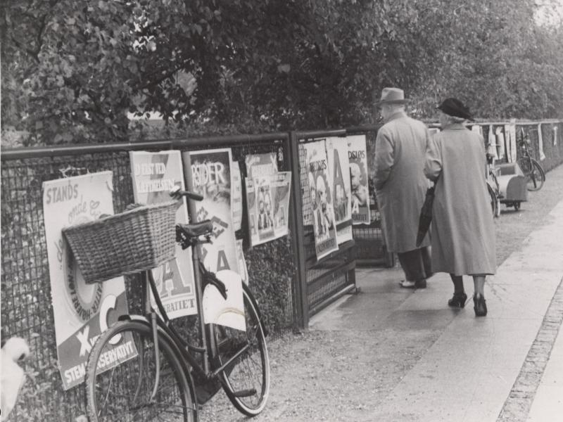 Valgplakater langs halvmur. En cykel står lænet op af muren.