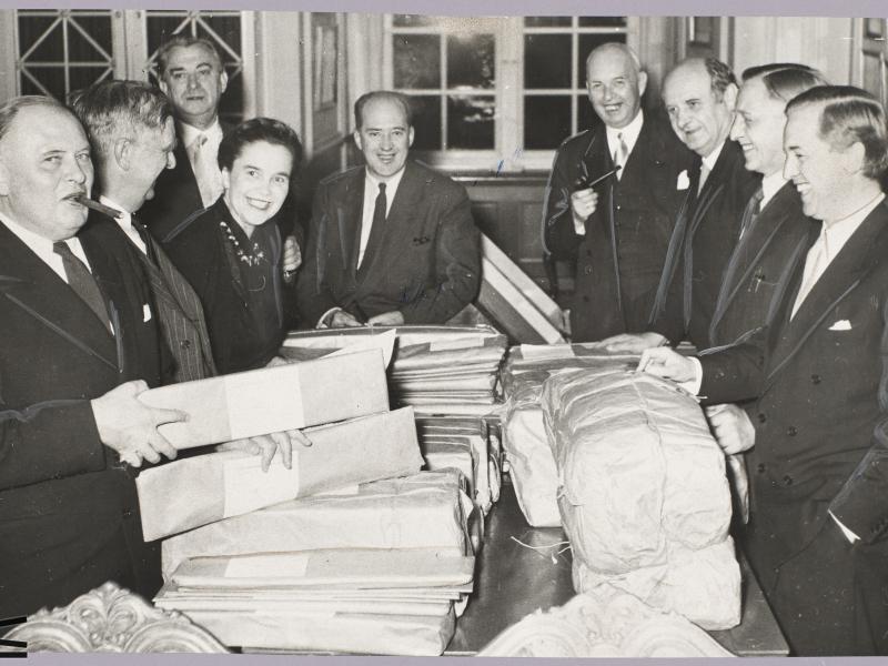  Men and a woman count votes around a large table