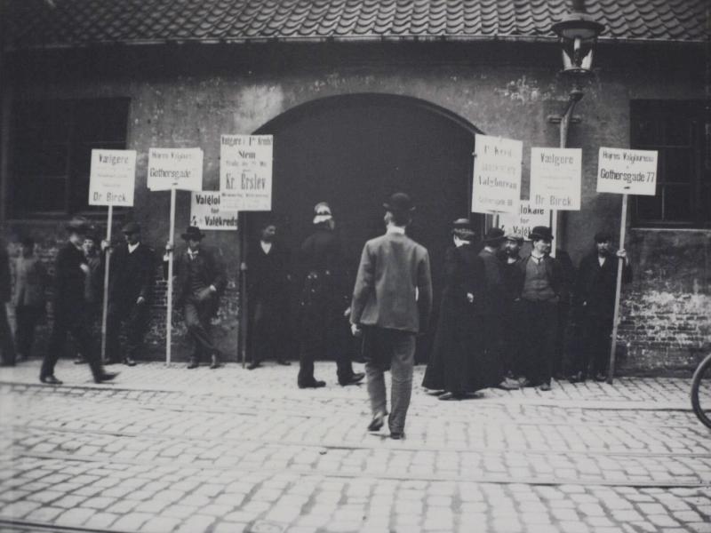 Man walks towards entrance where people are demonstrating outside with placards