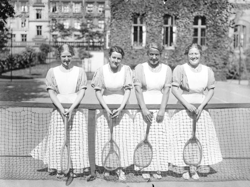 Fotografi af fire kvinder på en tennisbane.
