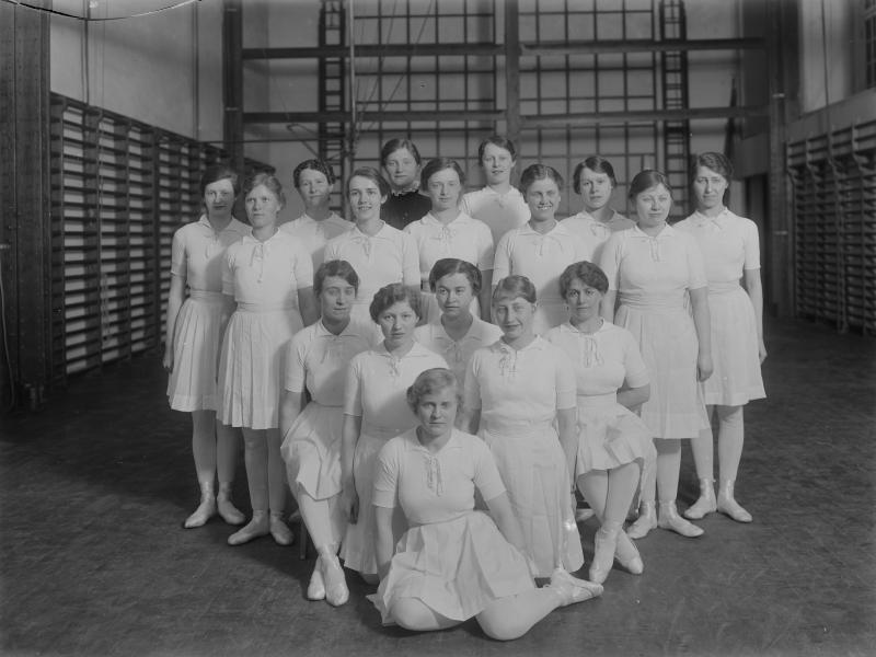 Fotografi af en gruppe kvinder iført gymnastikdragter i en gymnastiksal.