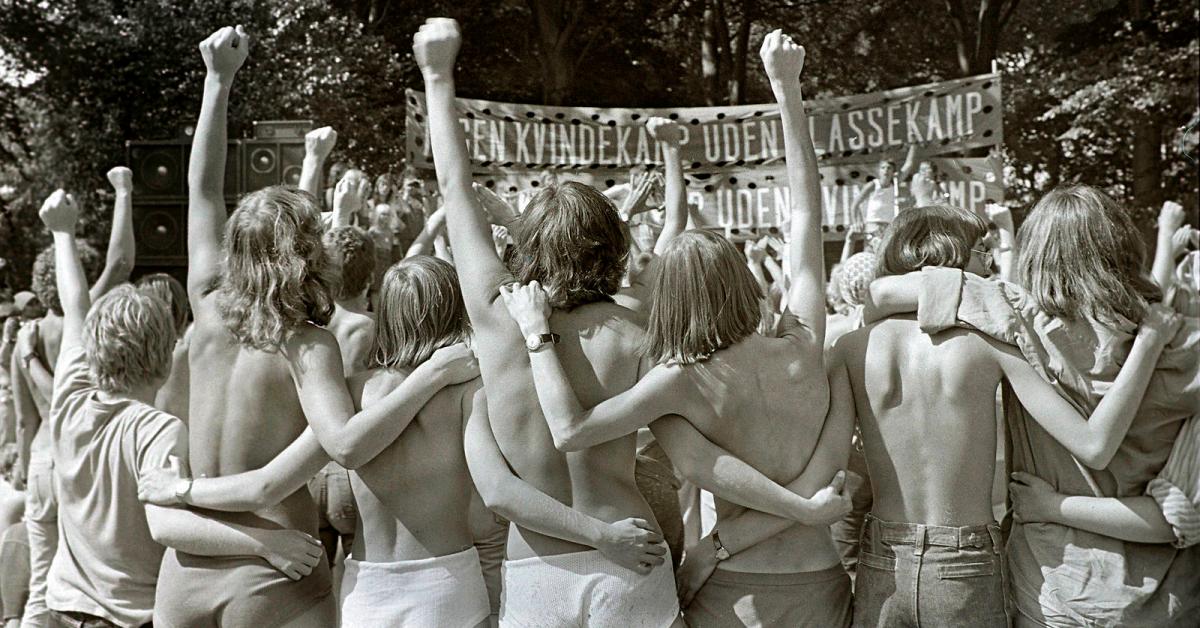 En flok halvnøgne mennesker med ryggen til og armene om hinanden