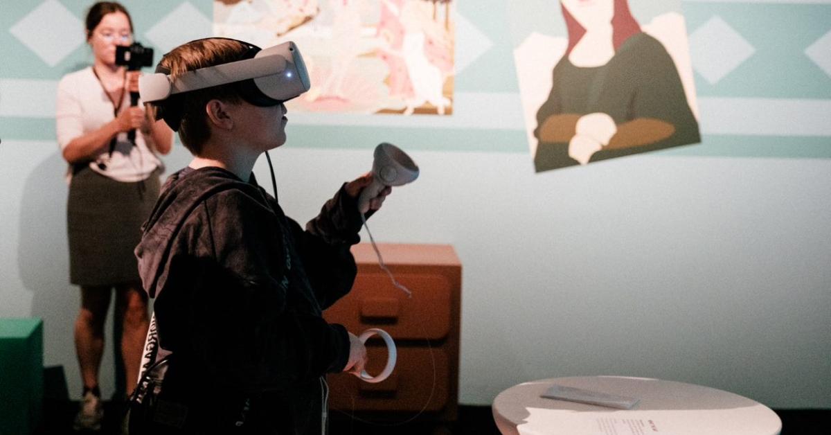 Billede af en dreng, der står med VR-biller på og en controller i hånden.