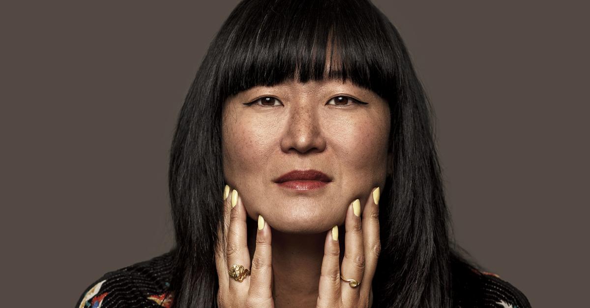 A woman has her hands on her chin and looks into the camera