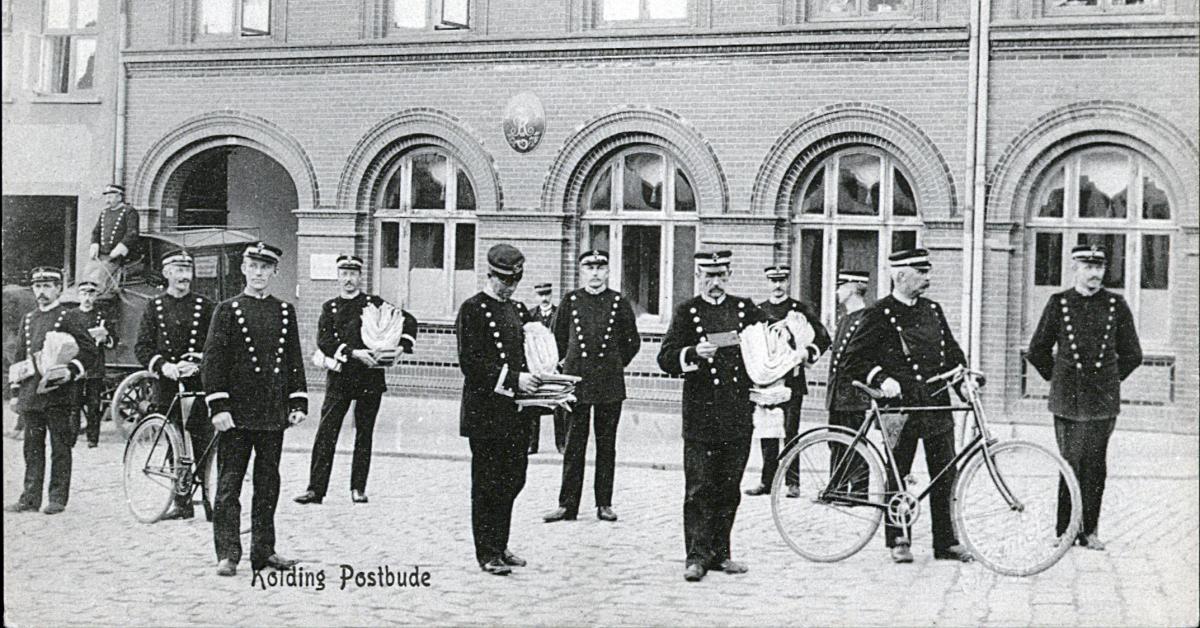 Postbude poserer foran posthuset i Kolding. Et par med cykler.